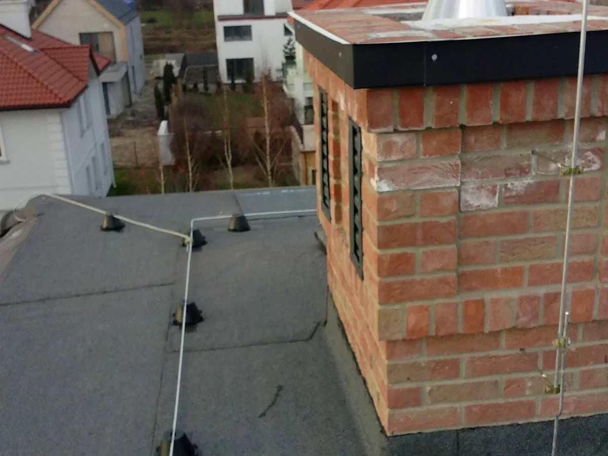 Instalacja odgromowa prowadzona przy kominie na płaskim dachu